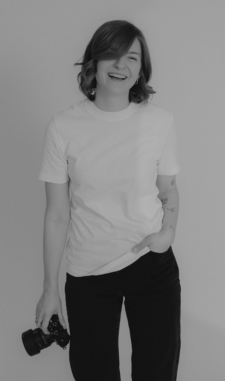 Bebildert Fotografie - Eva-Maria Griese Lachende Person mit kurzen Haaren, die entspannt auf einen Stuhl gestützt ist.