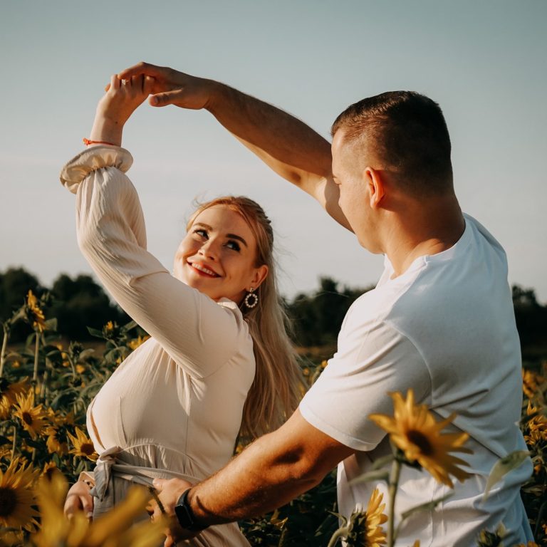 Lachendes Paar bei Sonnenschein in einem Sonnenblumenfeld