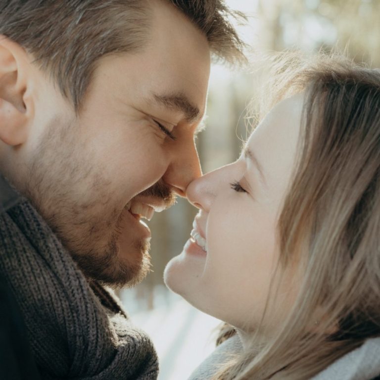 Paar Fotoshooting Paar umarmt sich liebevoll, die Köpfe nahe beieinander, in einer natürlichen Umgebung.